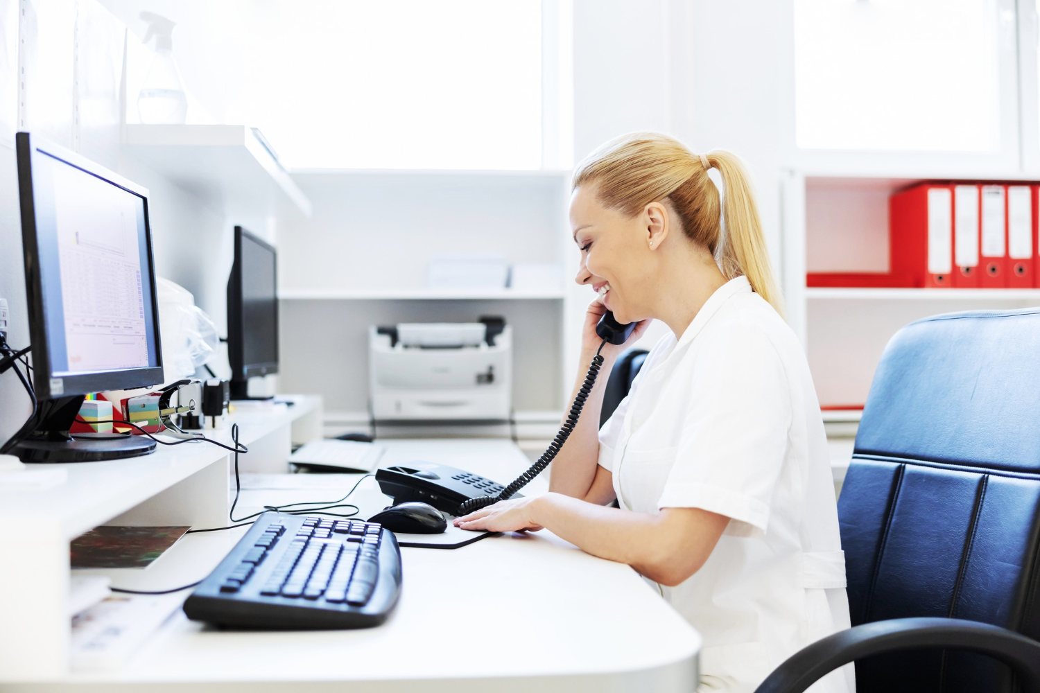 Praxismitarbeiterin am Empfang während eines Telefonats